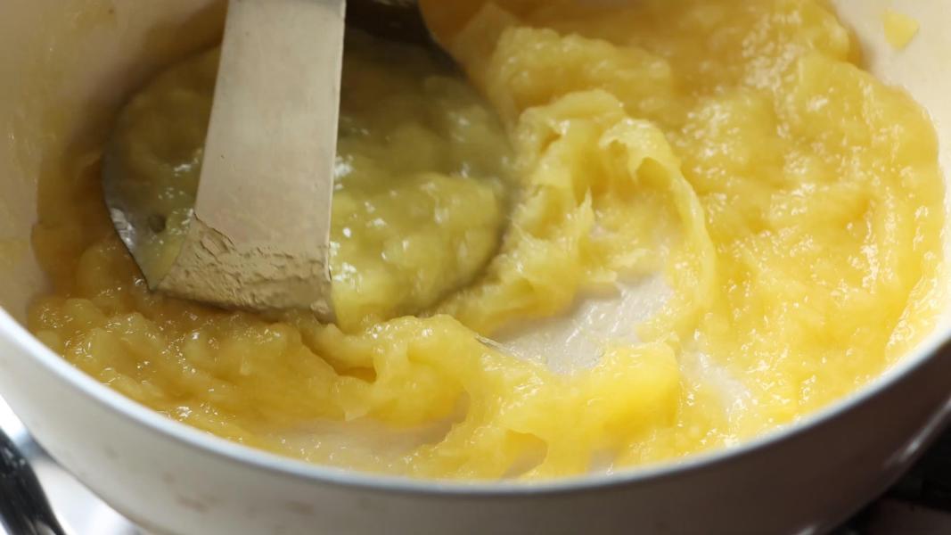 mashing cooked mango using a potato masher