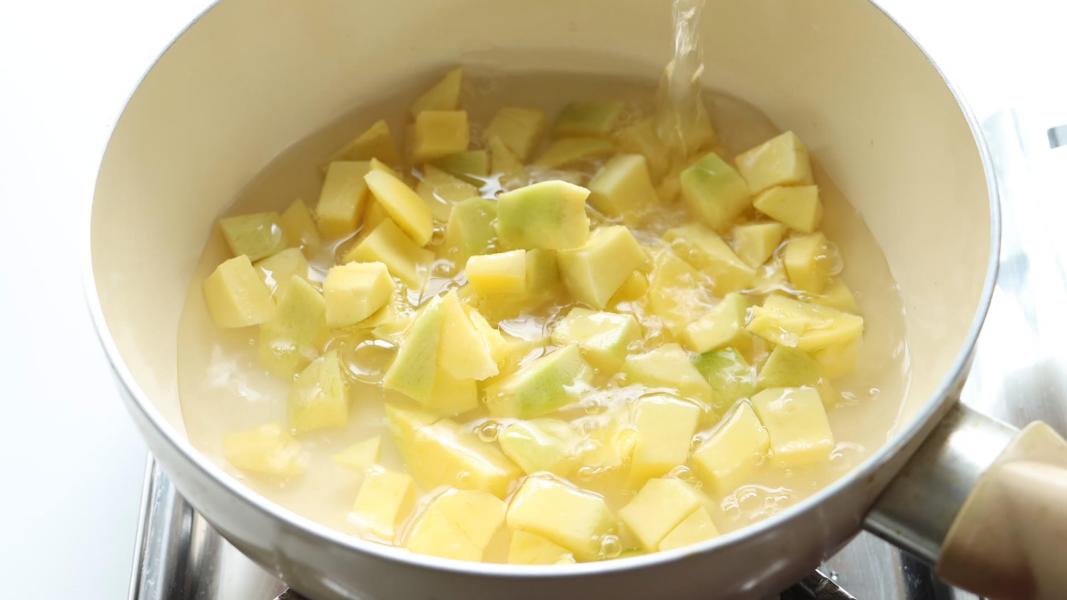 cooking mango pieces with water in a sauce pan.