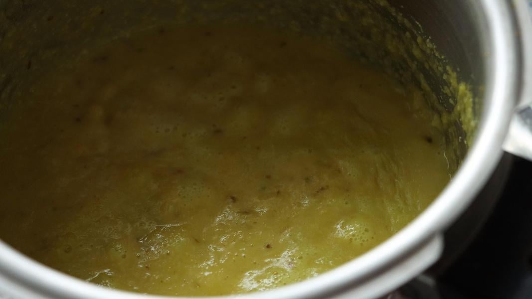 Dal and coconut-spiced mixture is simmering in a pressure cooker.
