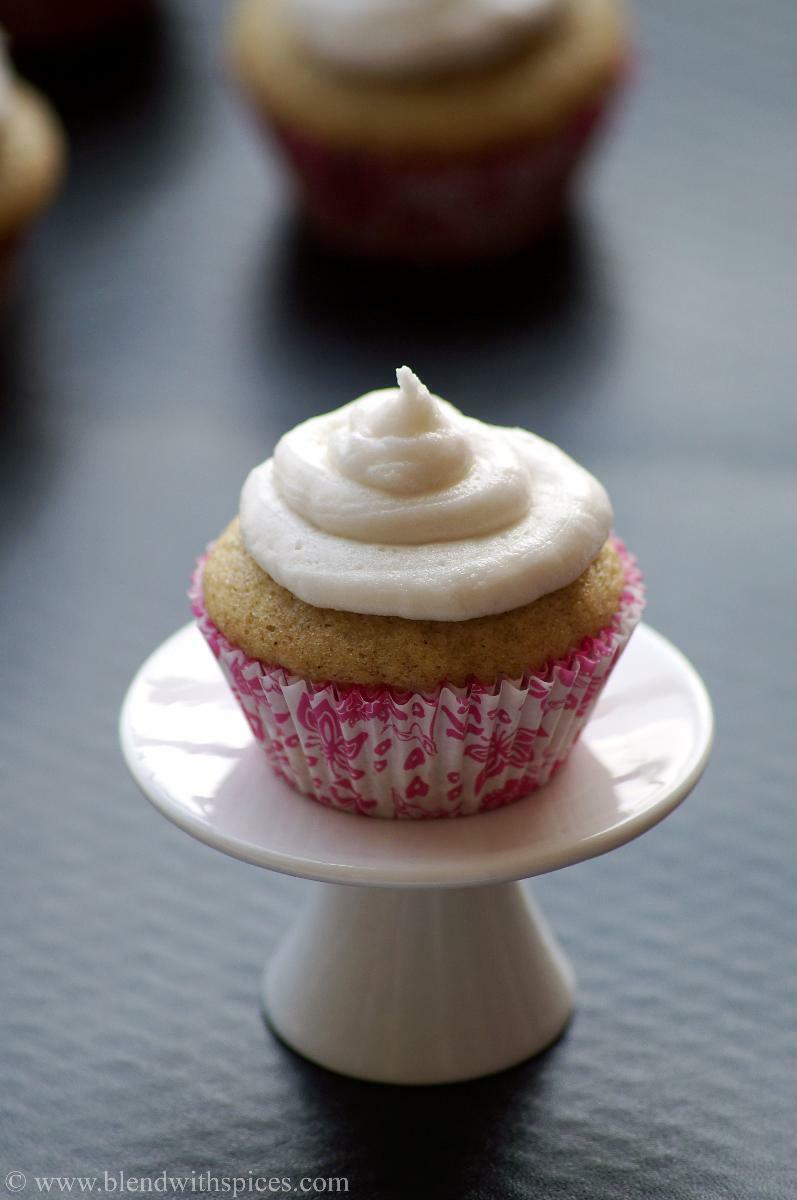 Eggless cardamom cupcake with vanilla frosting placed on a small cupcake stand