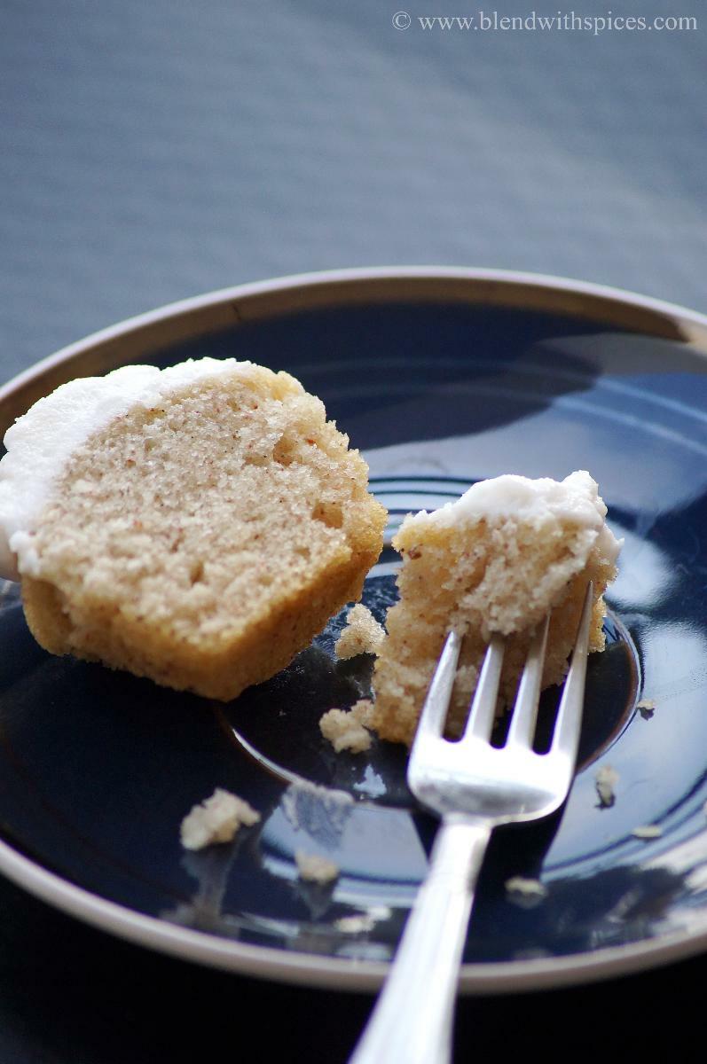 Vegan cardamom cupcake cut into half and served on a blue plate with a fork.