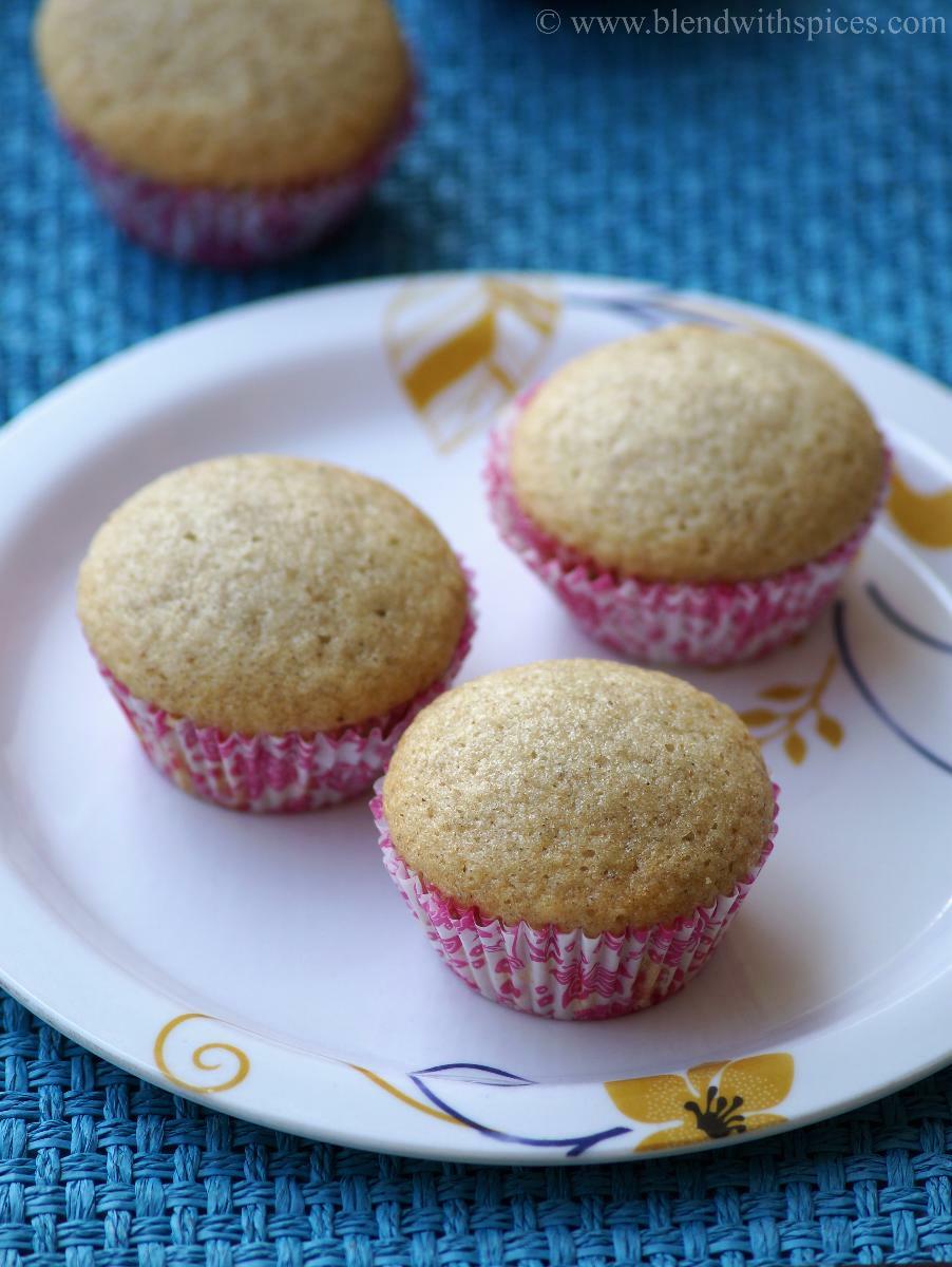 Baked eggless cardamom cupcakes are placed on a plate to add the frosting.