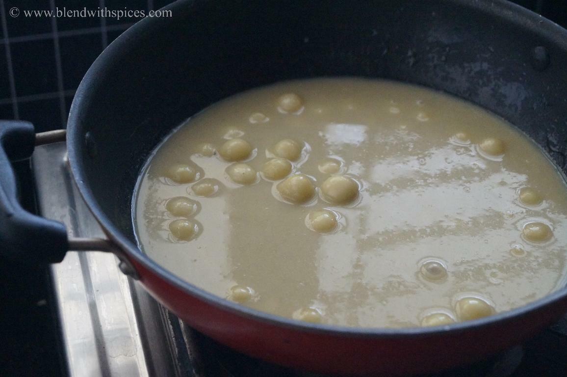 Adding coconut milk to the cooked rice flour dumplings for making paal kozhukattai.