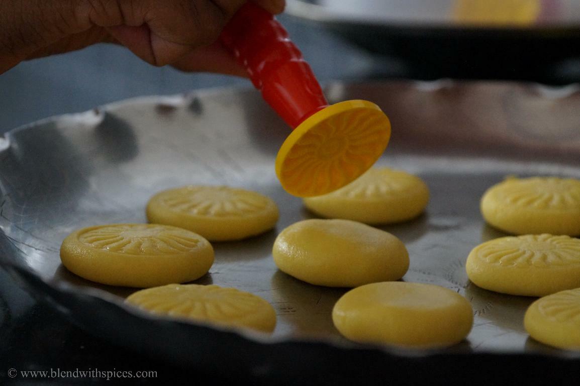 Shaping kesar peda by pressing with a peda mould to create a decorative pattern.