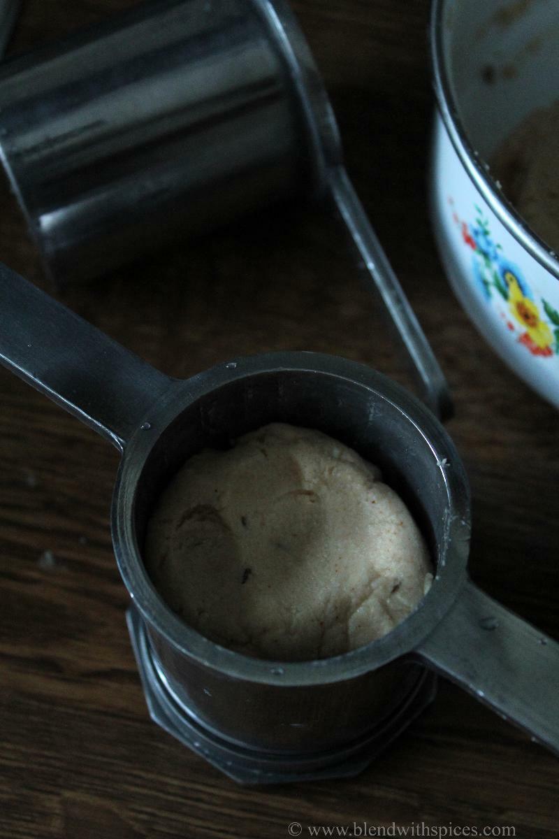 Small steel murukku press is filled with murukku dough.