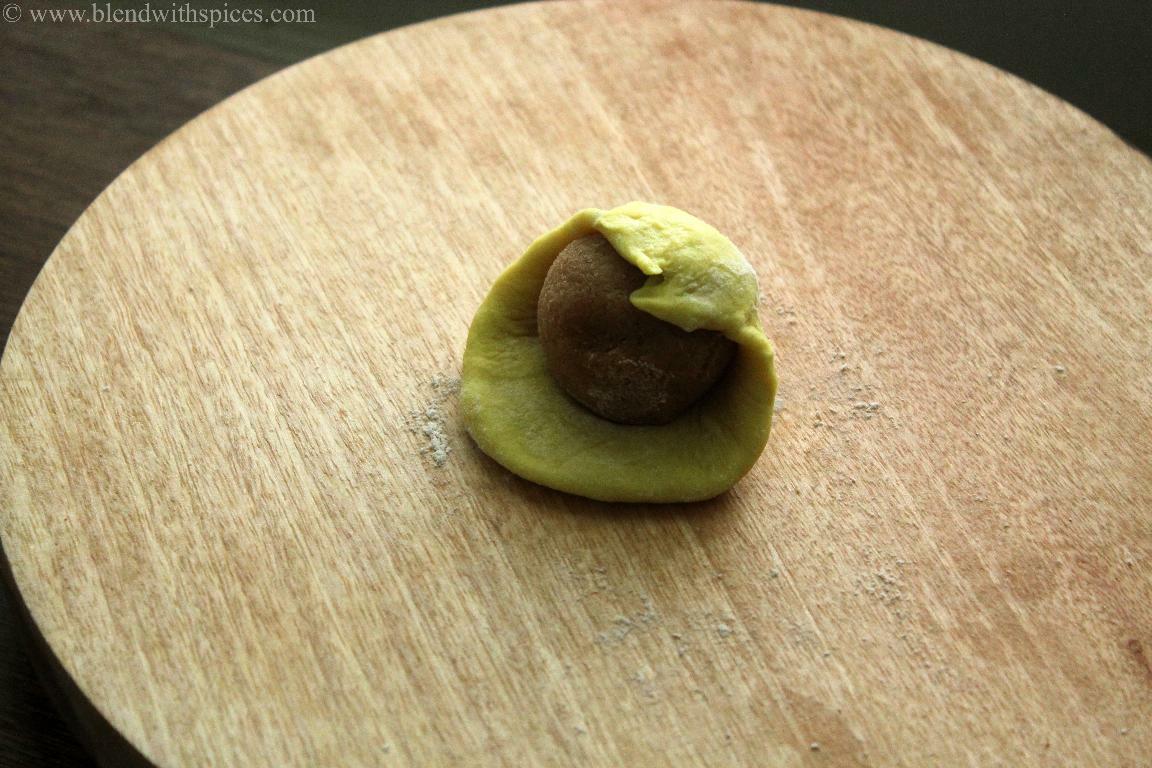Stuffing coconut jaggery mixture into dough to roll thengai poli