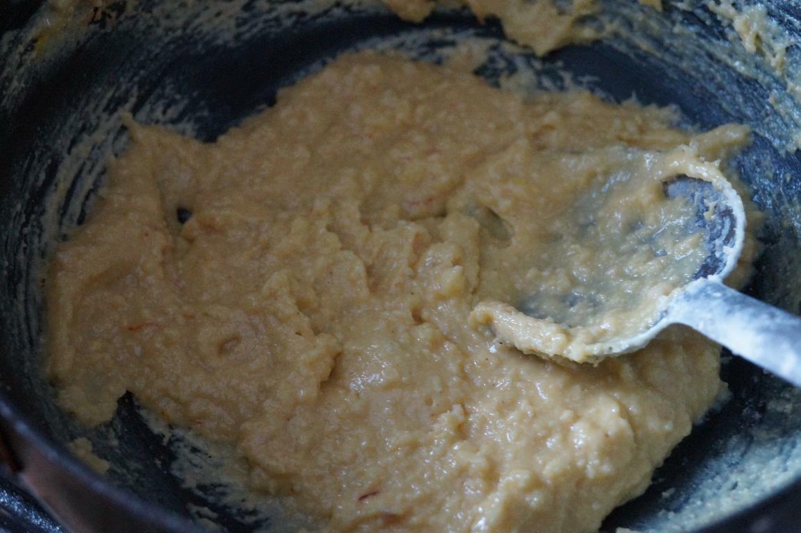 Cooking khoya mixture with sugar and saffron until thick and smooth for burfi.