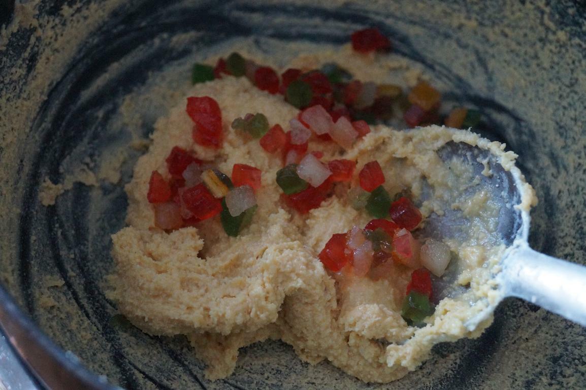 Adding tutti frutti to cooked khoya mixture for making tutti frutti kesar burfi.