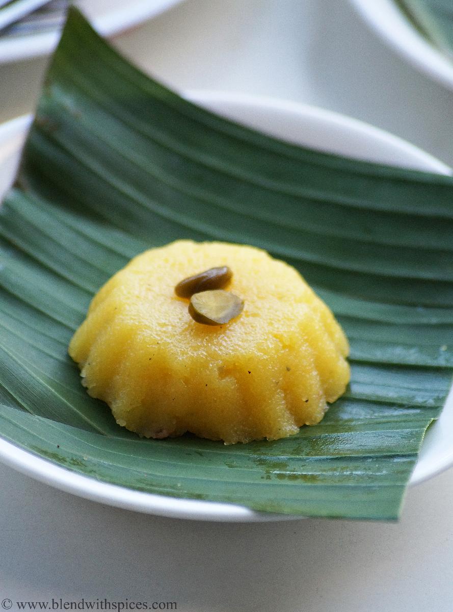 yellow colored Indian pudding topped with pistachio and served on a plantain leaf
