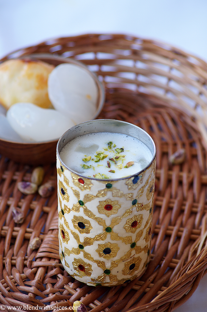 A glass of summer beverage with toddy palm seeds, and milk garnished with pistachios