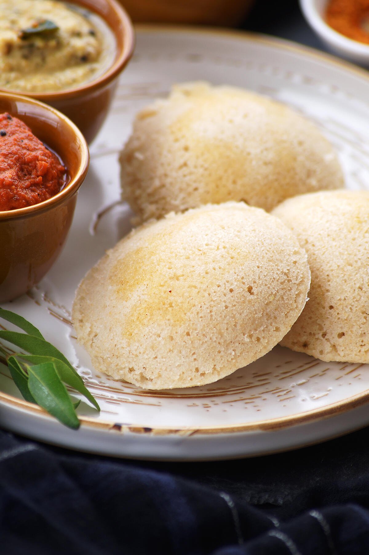 soft south indian oats idli served on a white plate and topped with ghee.