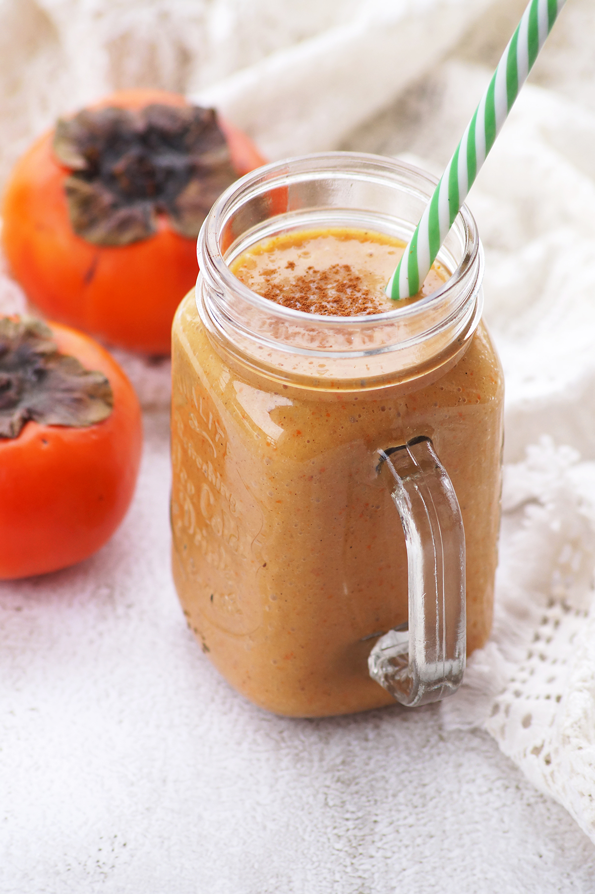 a glass jar full of persimmon smoothie, topped with cinnamon