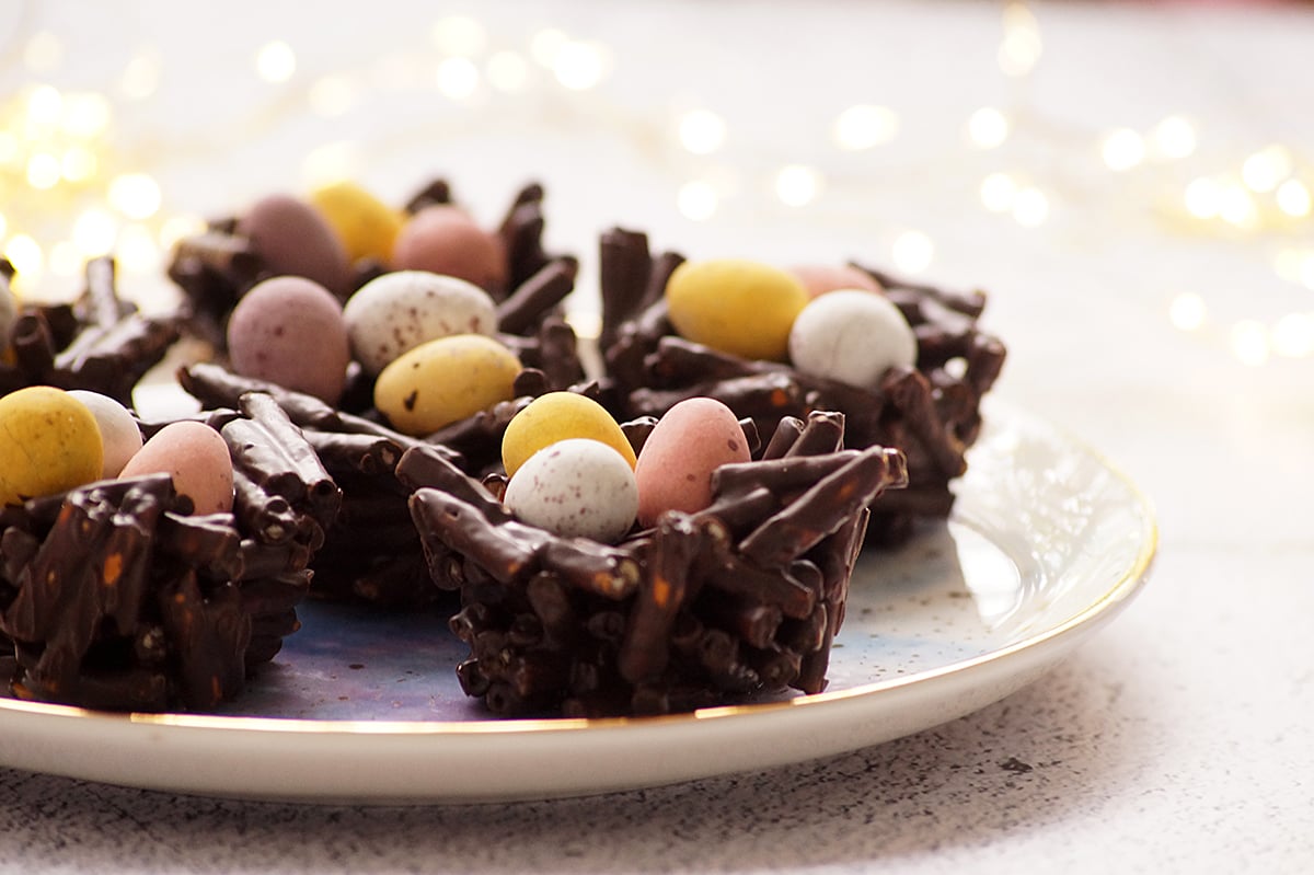 A few pieces of Chocolate Pretzel Easter Nests topped with mini eggs on a serving platter