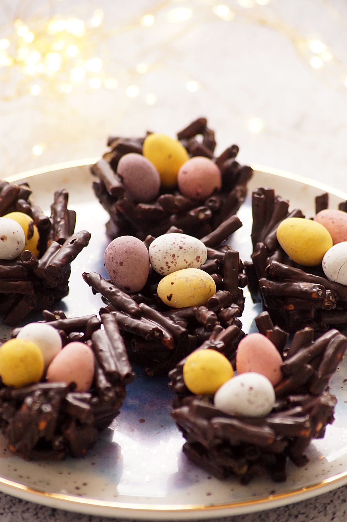 A few pieces of Chocolate Pretzel Easter Nests topped with mini eggs on a serving platter