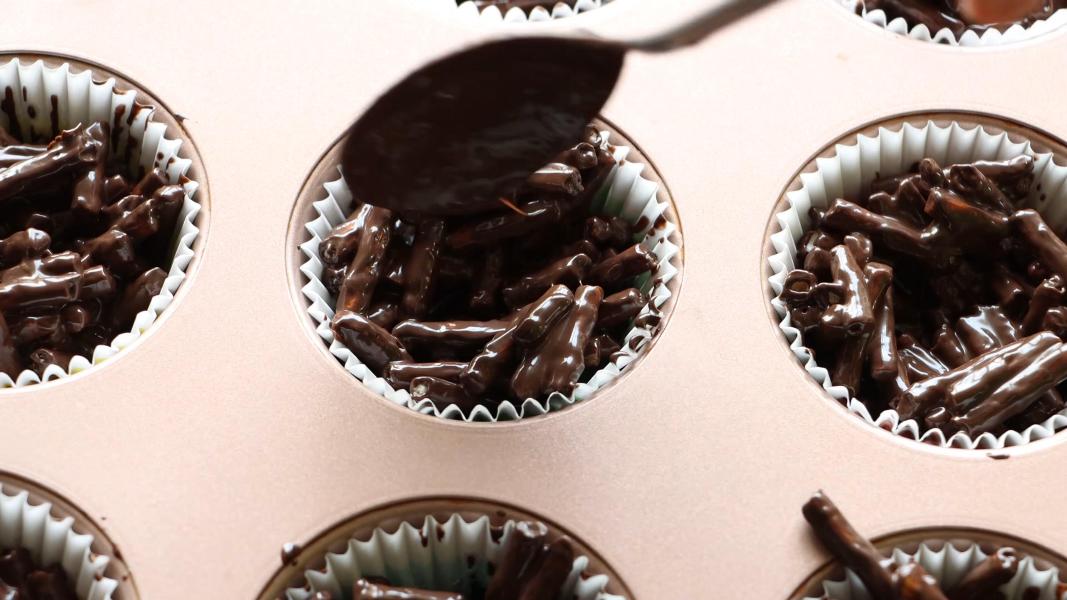 Adding spoonful of pretzel chocolate mixture into lined muffin tray.