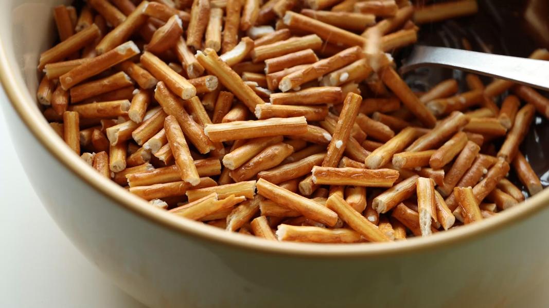 Pretzel pieces are added to the melted chocolate to be coated.