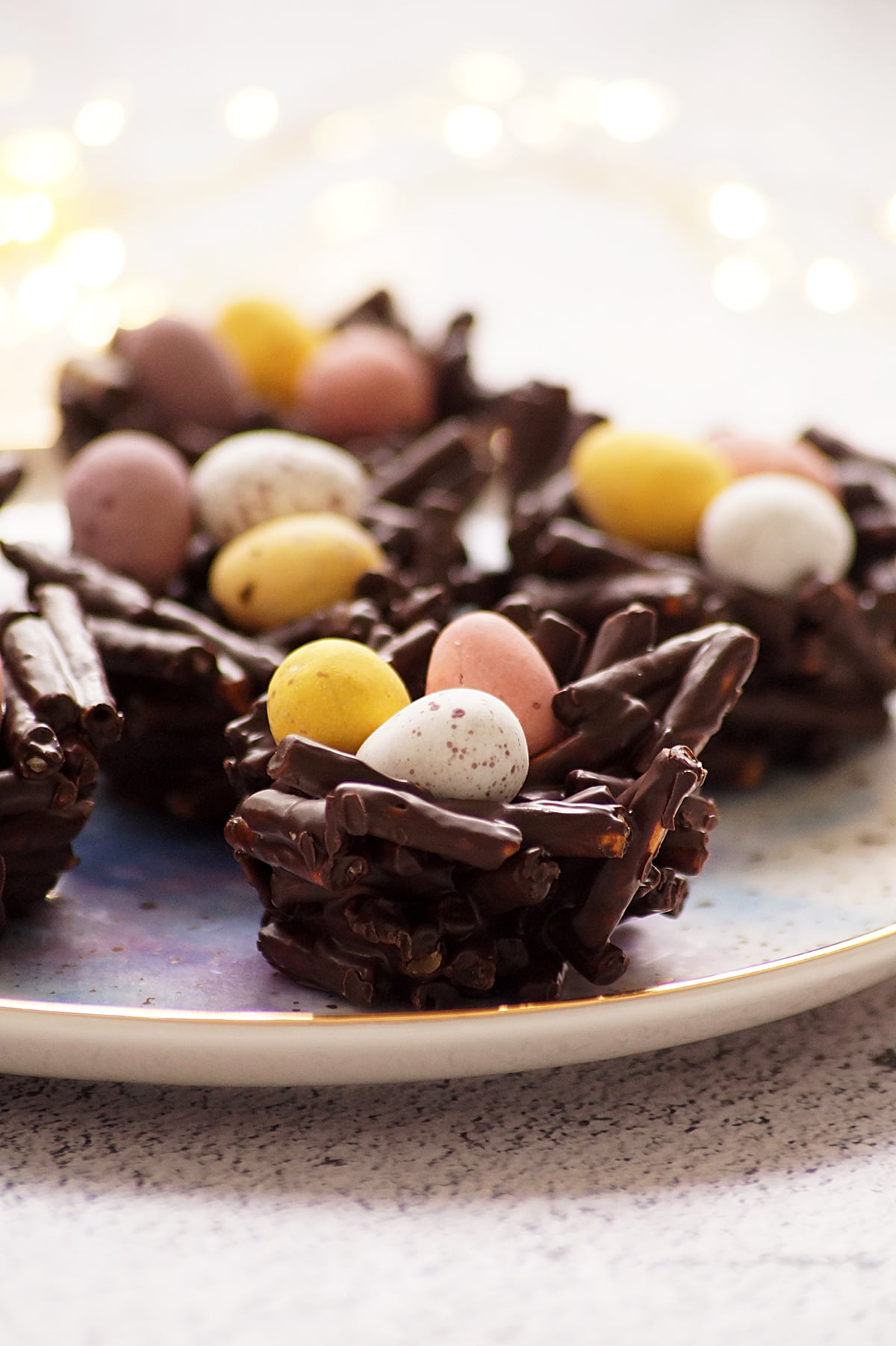 A few pieces of Chocolate Pretzel Easter Nests topped with mini eggs on a serving platter