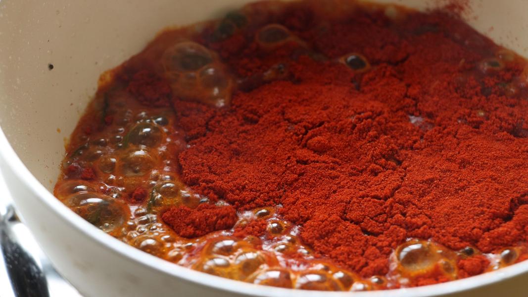 Fenugreek powder and kashmiri red chilli powder added to the tempered tadka to make mango pickle