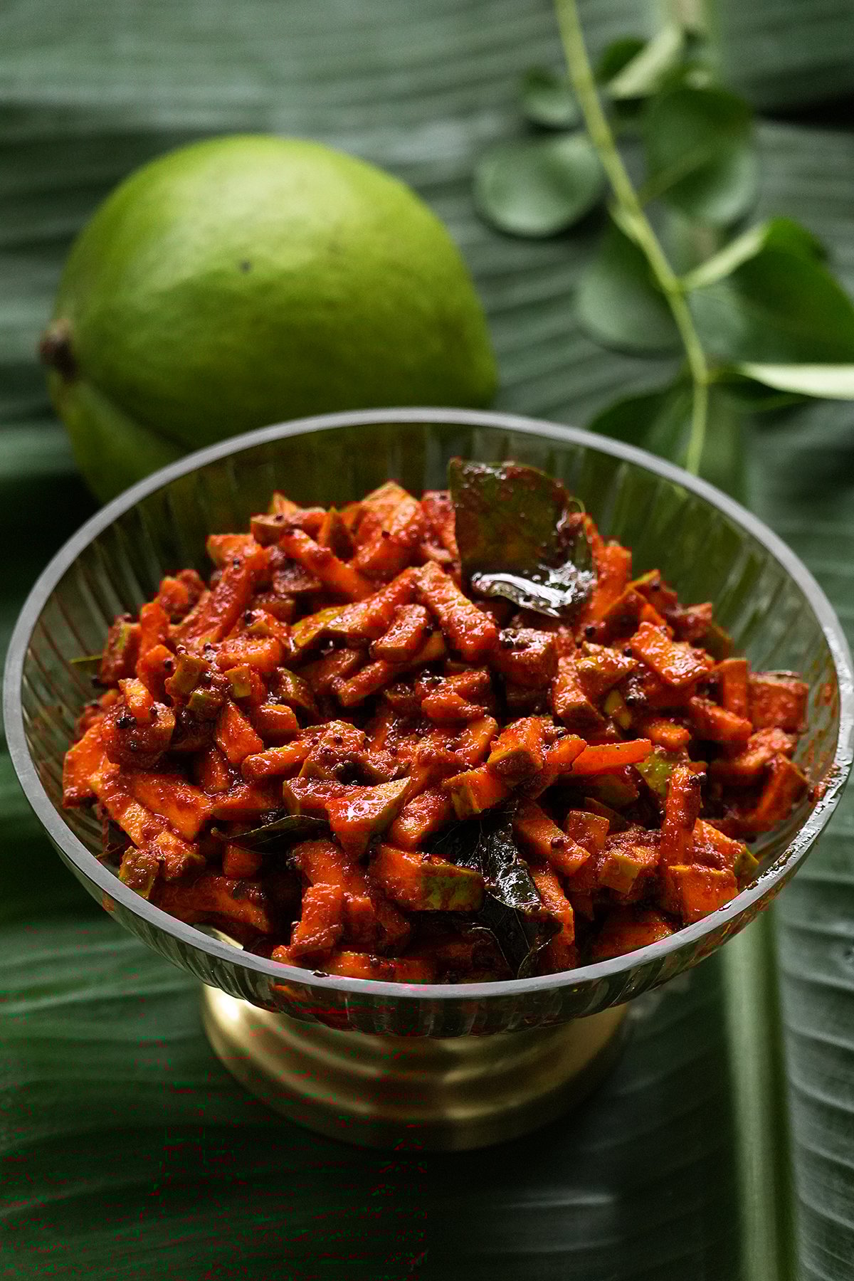 kerala style instant kadumanga achar served in a glass bowl and placed on a banana leaf