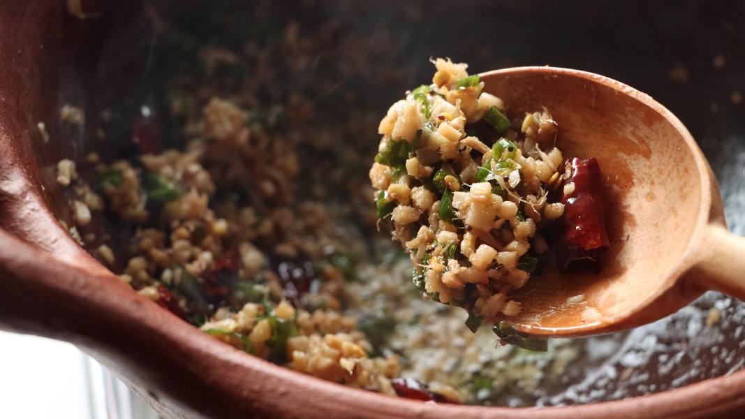 A portion of roasted ginger and green chilies in a wooden spoon