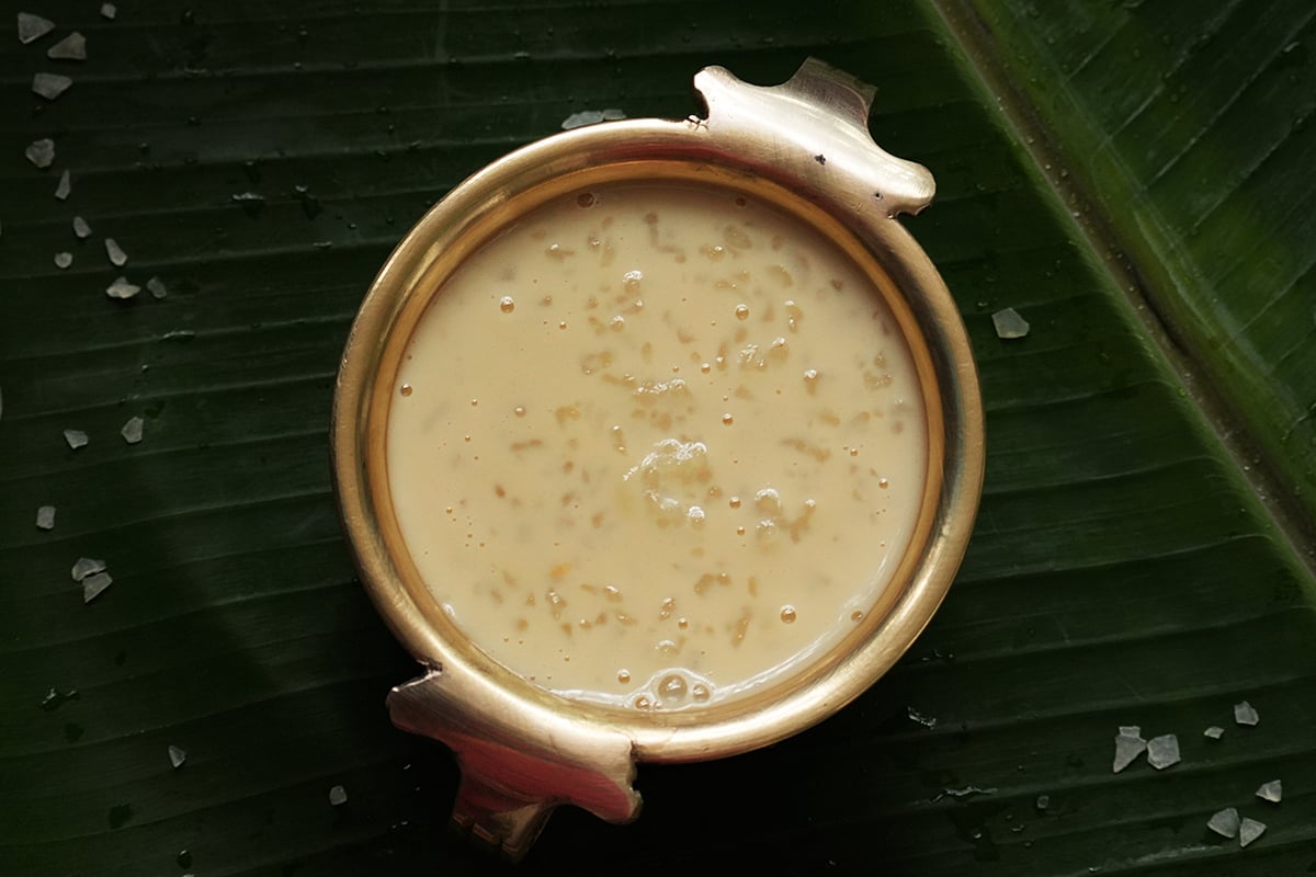 A little brass bowl full of kerala palada payasam placed on a banana leaf.