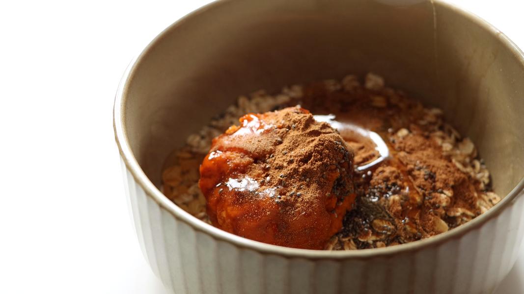ingredients are added to a ceramic mixing bowl to make Pumpkin pie overnight oats