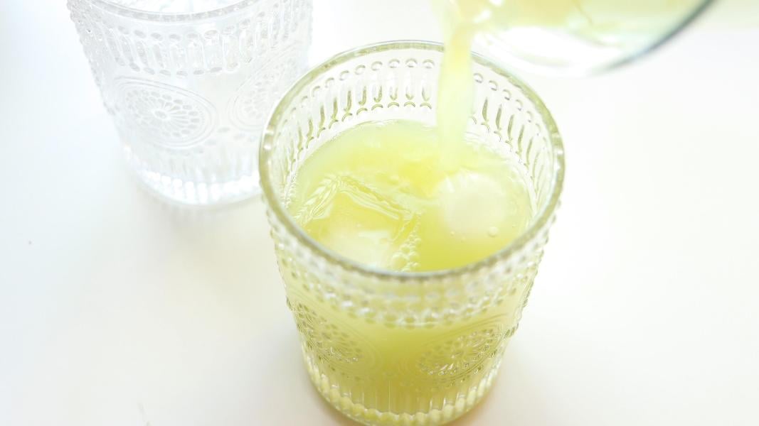 Pouring green apple juice into a serving glass