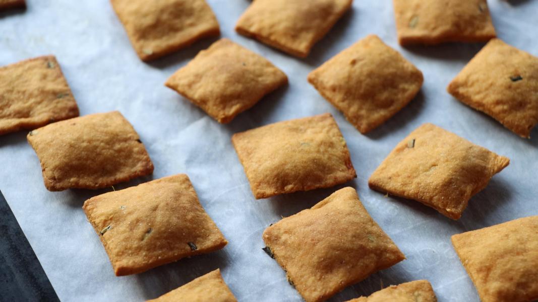 Baked sweet potato crackers cooling on a baking sheet lined with parchment paper.