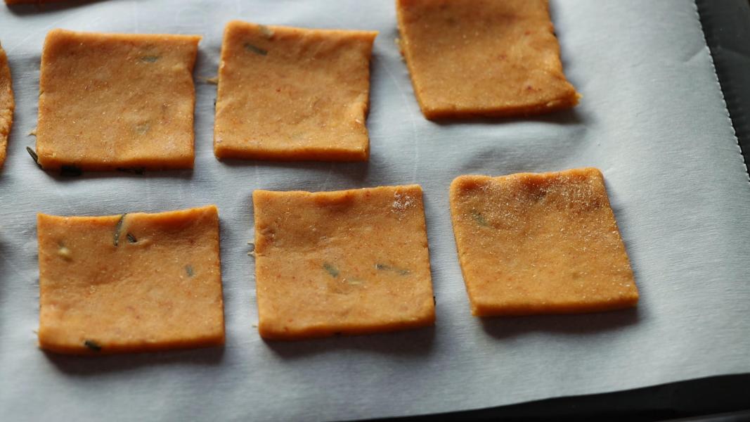 Square cut sweet potato cracker pieces are placed on a lined baking tray