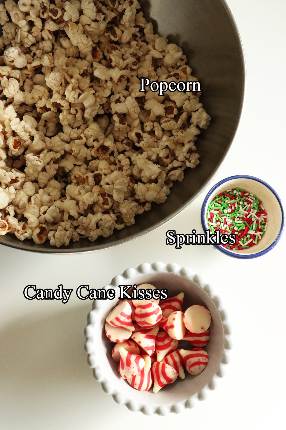 Ingredients needed for candy cane kiss popcorn, including popcorn, candy cane kisses and sprinkles