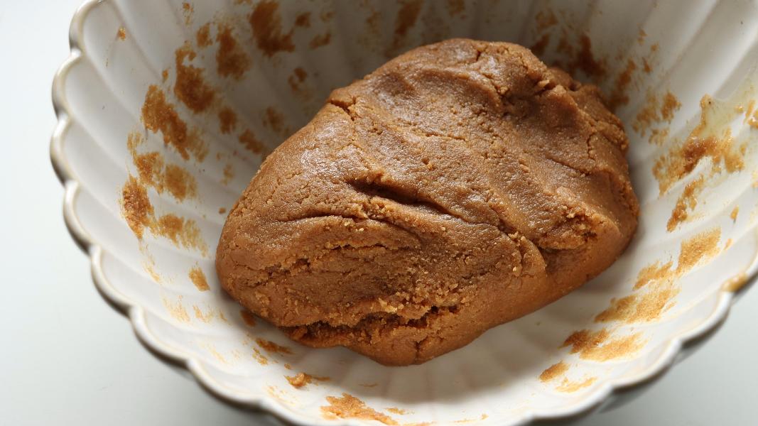 Cookie crumbs and condensed milk were mixed together and made a dough in a white bowl. 