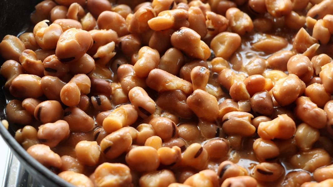 Fava beans simmering in a pot along with spices for making foul medames.