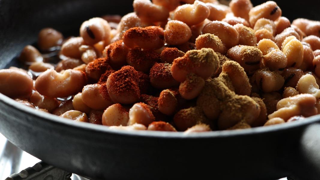 Canned fava beans / foul medammas and little water in a pan topped with paprika, cumin powder and salt while preparing ful medames.