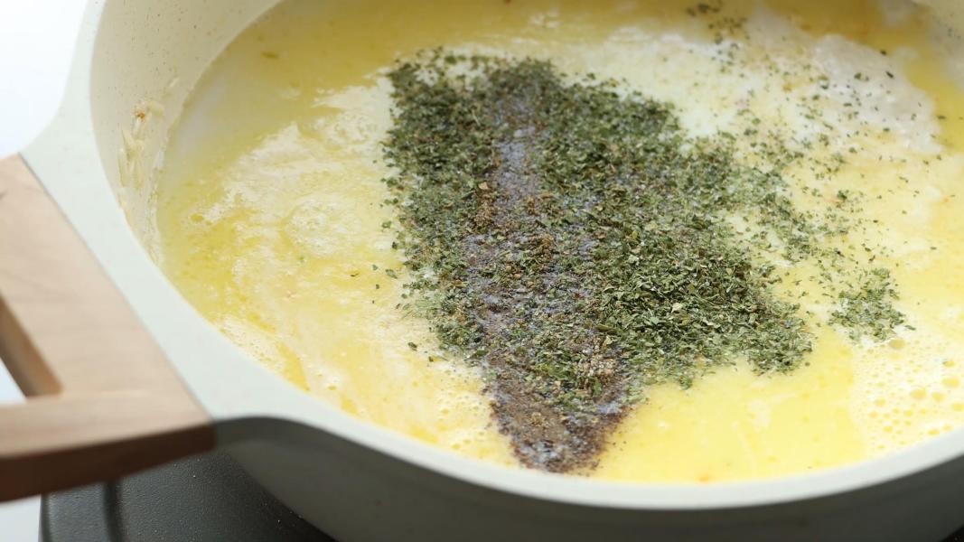 Adding dried parsley, salt and black pepper powder to the rice, milk mixture for parmesan rice.