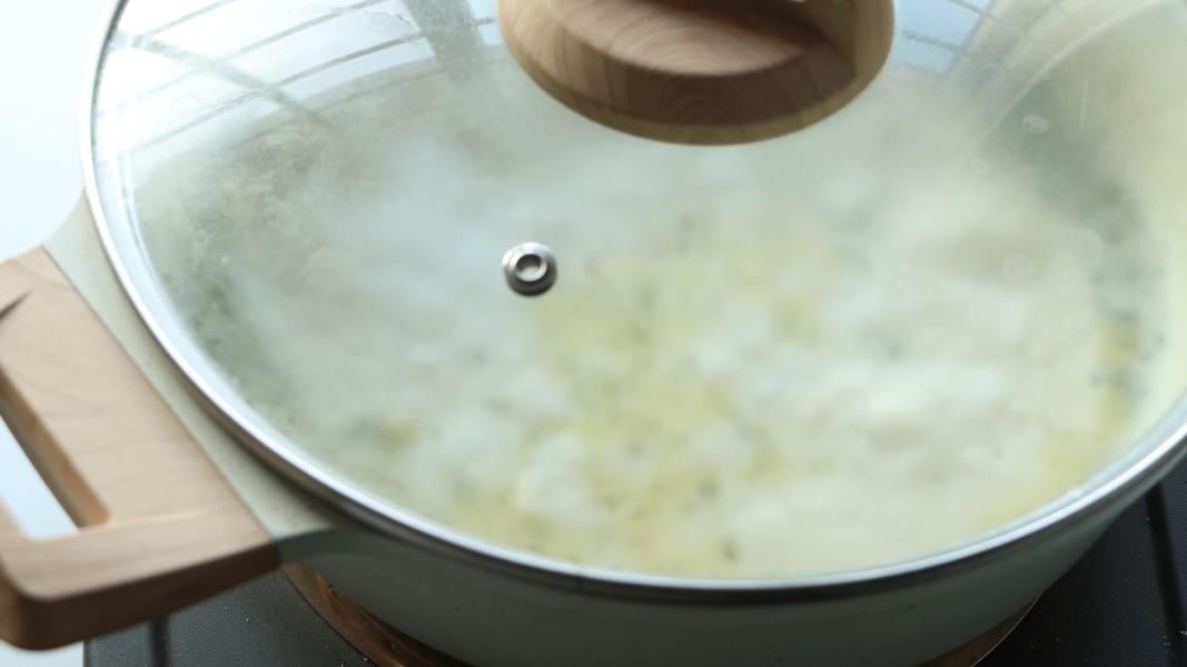 Covering the pan and simmering it until the rice is tender.
