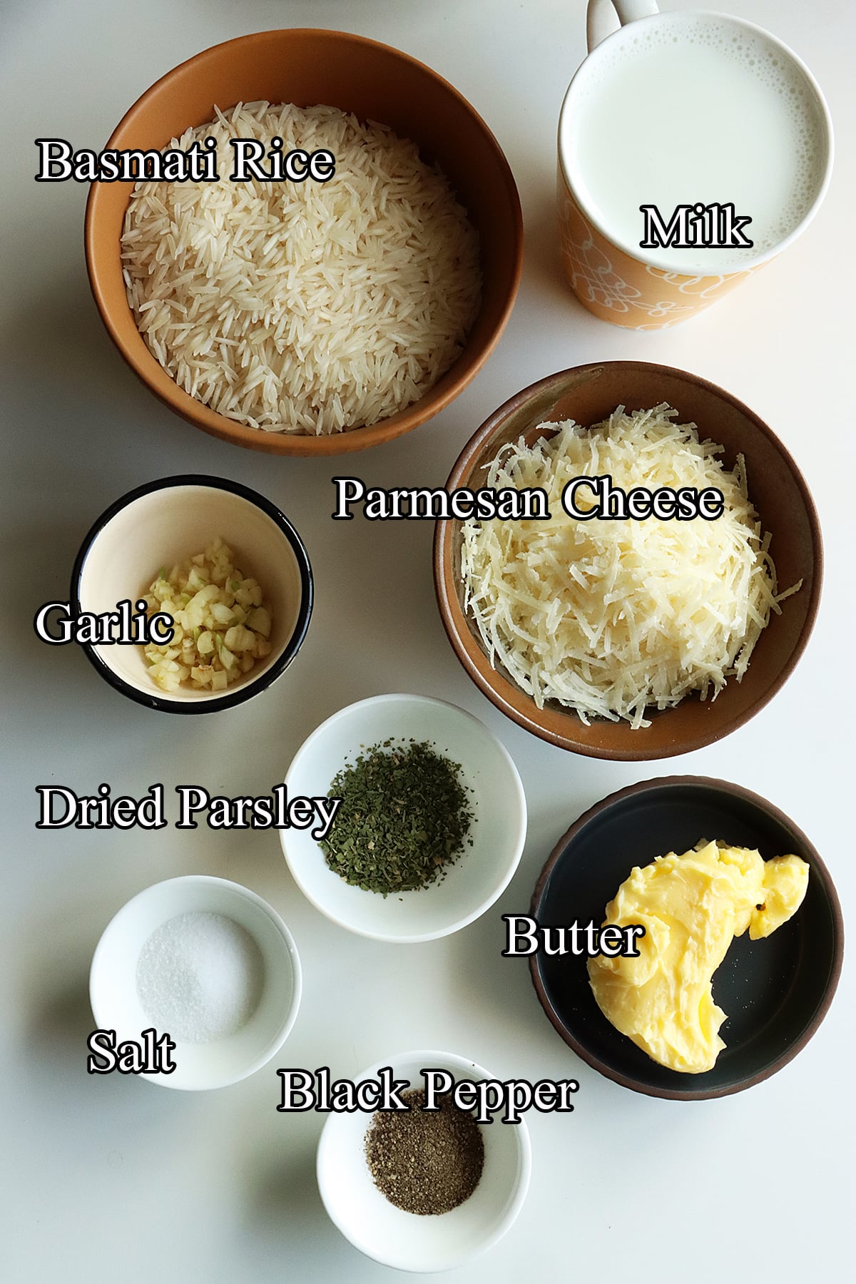 Ingredients for Parmesan rice, including long-grain rice, Parmesan cheese, garlic, butter, milk, dried parsley. salt and black pepper.