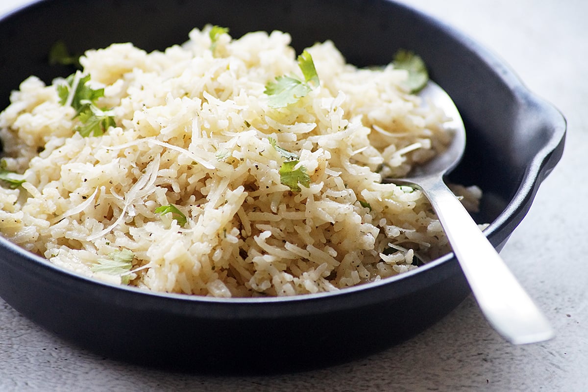 Garlic Parmesan rice with fluffy long-grain rice, grated Parmesan cheese, and fresh parsley served in a black bowl.