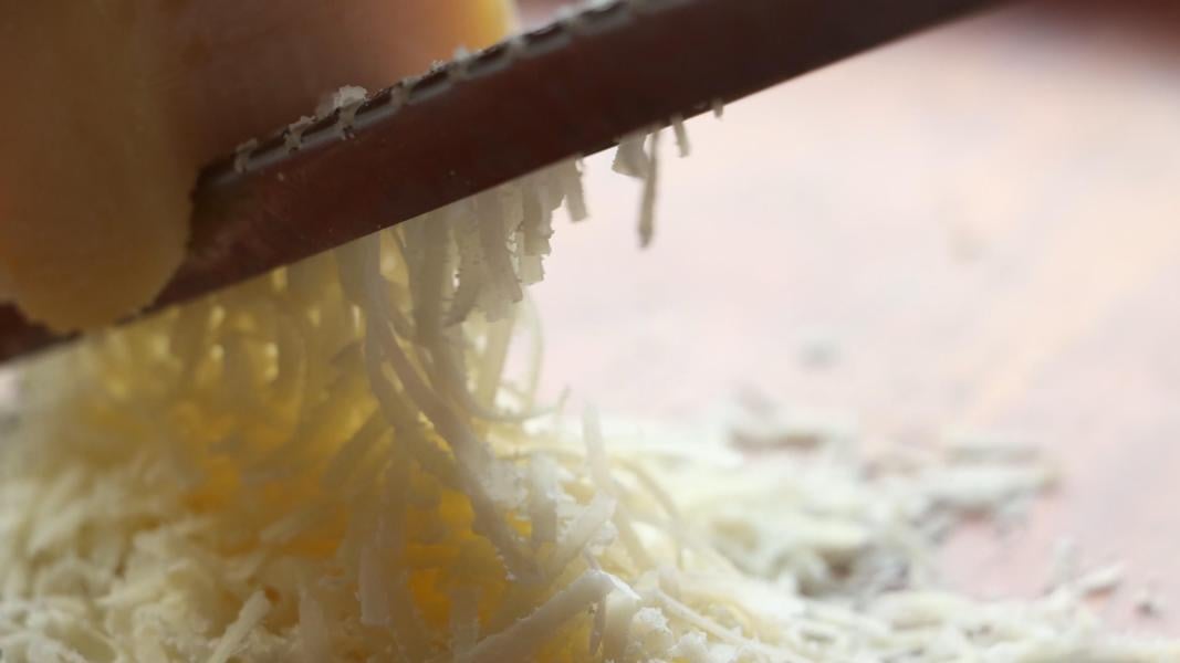 Grating parmesan cheese to make parmesan garlic rice.