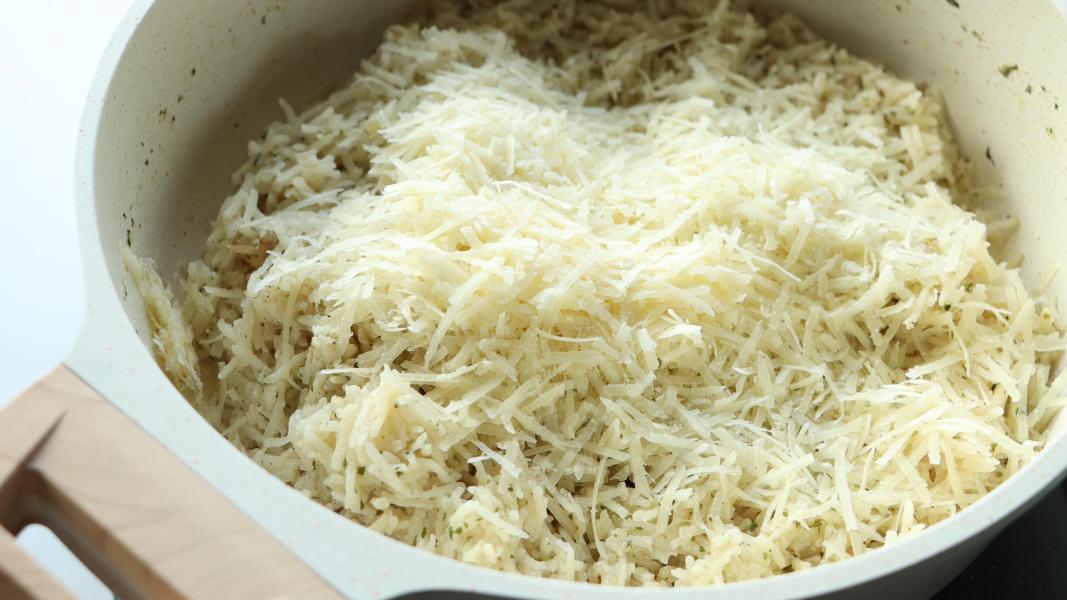 Adding grated parmesan cheese to the cooked rice for garlic parmesan rice