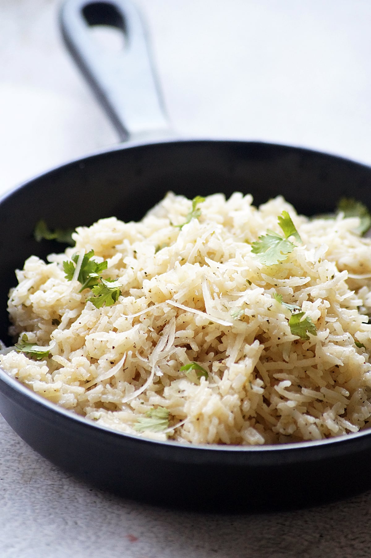 Garlic Parmesan rice with fluffy long-grain rice, grated Parmesan cheese, and fresh parsley served in a black bowl.