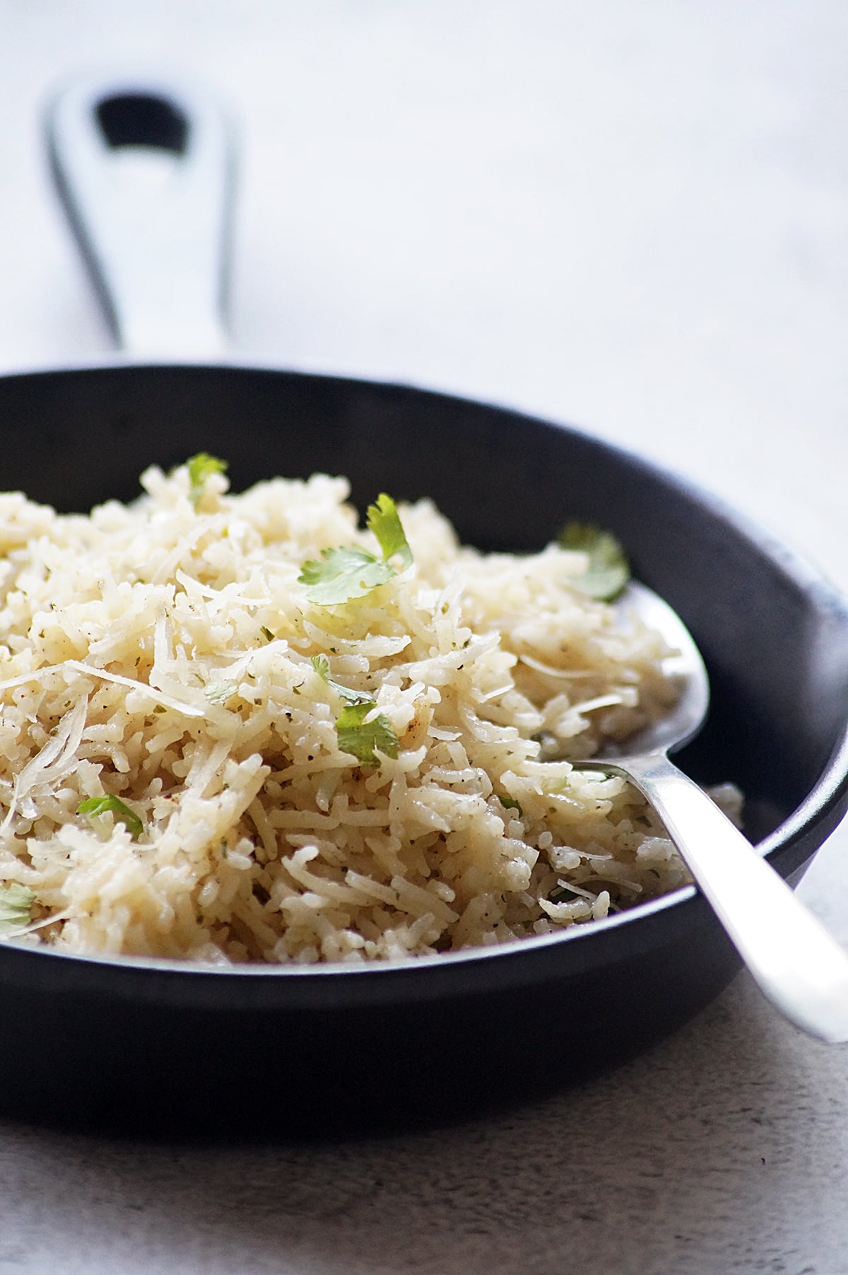 Garlic Parmesan rice with fluffy long-grain rice, grated Parmesan cheese, and fresh parsley served in a black bowl.